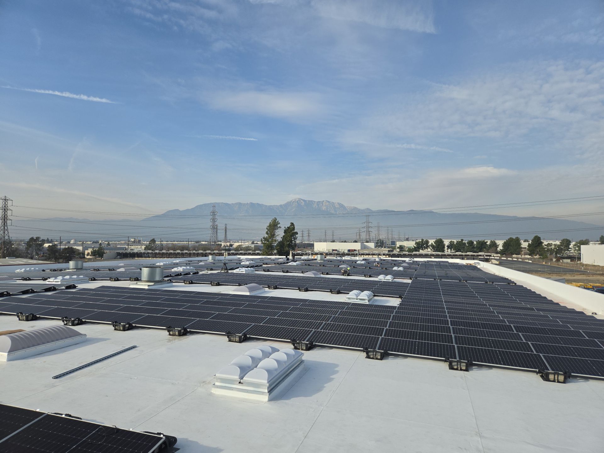 Commercial Energy Infrastructure Solar Array project on rooftop with cloudy sky in the background
