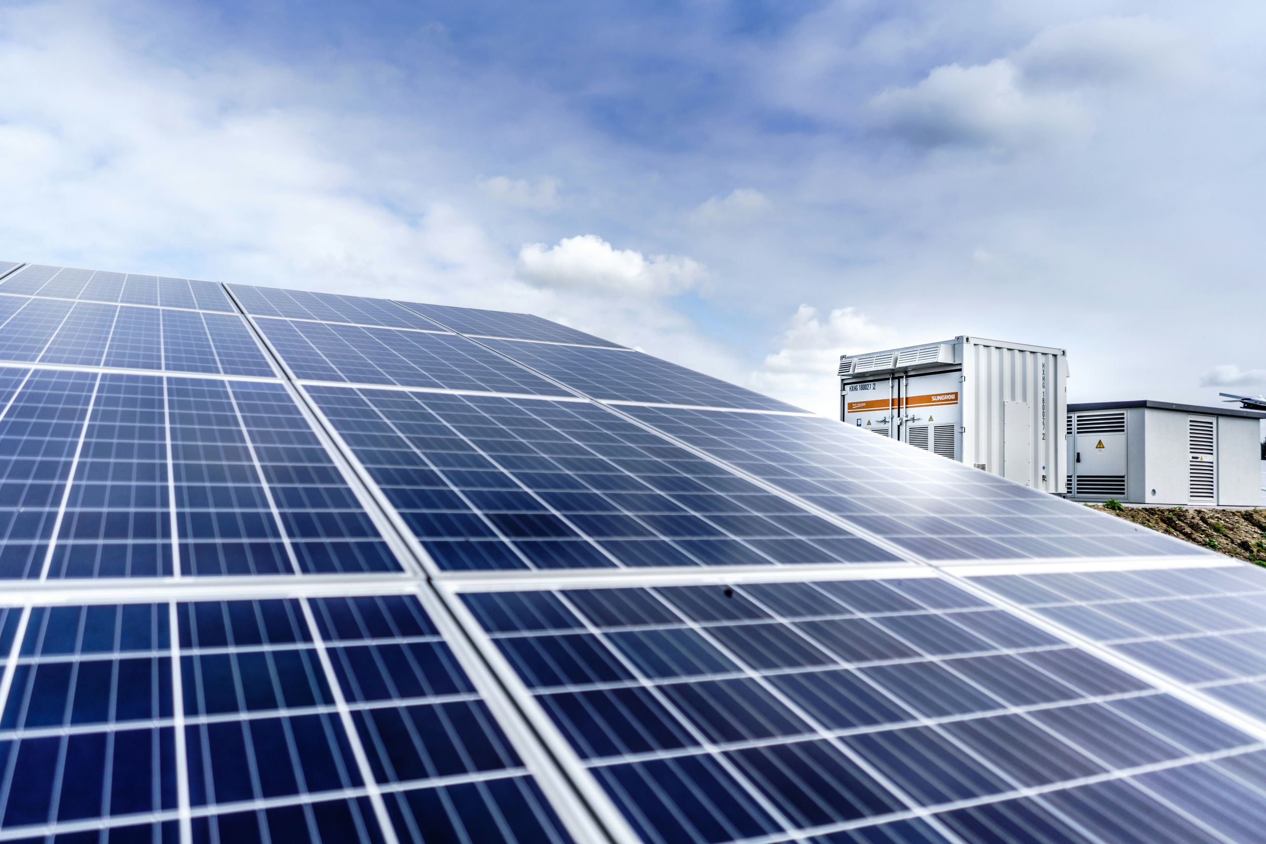 Solar panel in the foreground with a battery in the background
